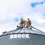 First responders wearing PPE on top of a grain bin performing a rescue